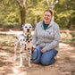 Woman kneeling on a path in a park with a Dalmatian dog.
